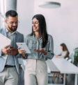 Shot of a two confident business persons talking in the work place. Two colleagues using a digital tablet while walking in a modern office. Businessman and businesswoman in meeting discussing business strategy. Business coworkers working together in the offic